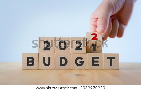 New year business plan concept in  2022. Male hand flips wooden cube and changes the inscription "BUDGET 20201" to "BUDGET 2022" with white  background, copy space. Use for banner and presentation.