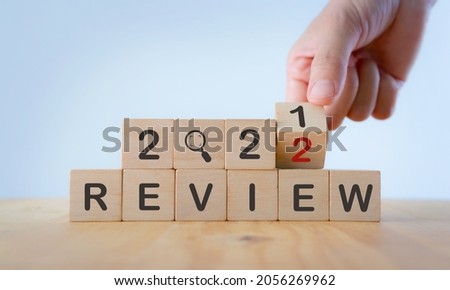 Business concept of planning 2022. Businessman hand flips a wooden cube and changes the inscription 'Review 2021' to 'Review 2022'. Beautiful white background, copy space. For the new year resolution.