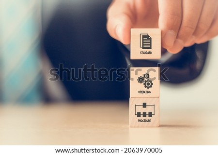 Standard Operating Procedure - SOP business concept. Instructions to assist employee  in complex routine operations. Hand hold wood cube with Standard Operating Procedure symbol on bright background.