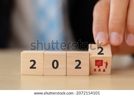 Training and knowledge sharing concept. Workforce and team training plan in 2022. Businessman flips the wooden cubes with 2022 and training symbols on beautiful white background and copy space.