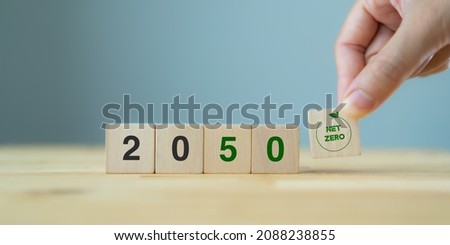 Net zero by 2050. Carbon neutral. Net zero greenhouse gas emissions target. Climate neutral long term strategy. No toxic gases. Hand puts wooden cubes with net zero icon in 2050 on grey background. 商業照片 © 