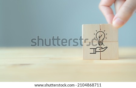 New idea, solution, suggestion concept.  Hand puts the wooden cubes with light bulb on hand icon on beuatiful grey background and copy space. Business review, strategy suggestion for business growth. Foto d'archivio © 