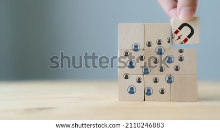 Attracting online customer and lead generation concept. Digital inbound marketing, customer retention strategy.Hand hold wooden cube with the icon big magnet to attract many people on grey background. Foto stock © 