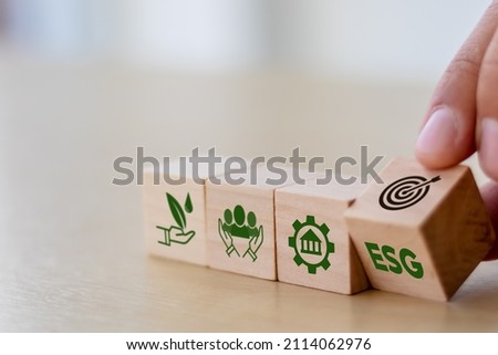 ESG concept of environmental, social and governance. Sustainable corporation development. Hand flips wooden cubes with target setting  to ESG icon with other ESG icons on bright background.Copy space. 商業照片 © 