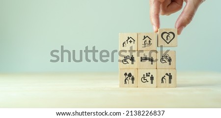 Elderly care concept. Hand holds wooden cubes with icons related to elderly care, medical, rehabilitation service, nursing care for enhancing quality of life in elder age. Used for banner, background Foto stock © 
