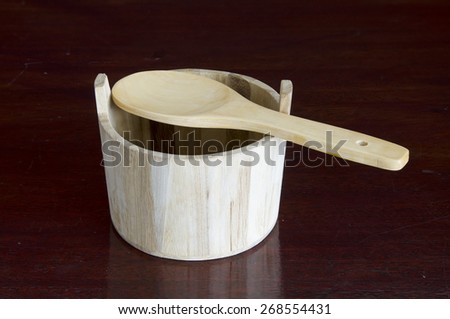 a wood bucket and spoon on a dark wooden table.