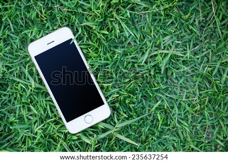 Mobile smart phone in green grass and black screen