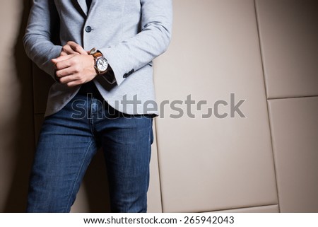 Businessman in gray suite,Blue jeans. Part of body. On beige color background