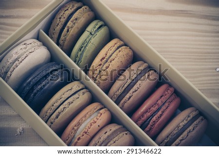 traditional french sweet dessert colorful delicious macarons in a rows in a box on wood background focus on red and green process on retro vintage tone