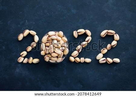The numbers 2022 are made from eating pistachios, new year and Christmas, healthy food and a symbol of the new year