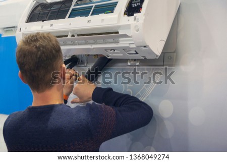 Worker mounts and connects the air conditioner on the wall of the house Сток-фото © 