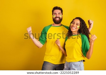 couple of brazil soccer supporters, dressed in the colors of the nation, black woman, caucasian man. Twisting and vibrating. Сток-фото © 