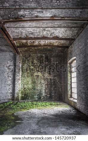 Inside of an old brick warehouse with light coming in through window making an ideal background for a spooky dungeon.