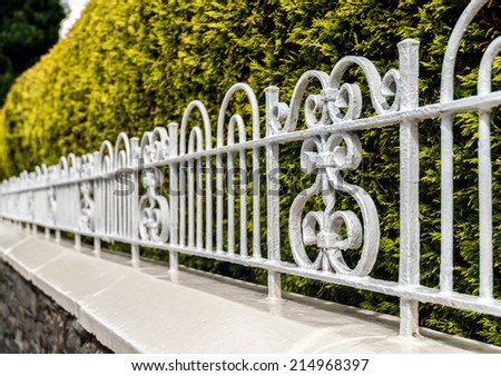 Ornate cast iron railing on a stone walled garden.