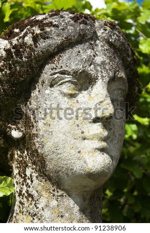 Weathered limestone figure head of garden statue.