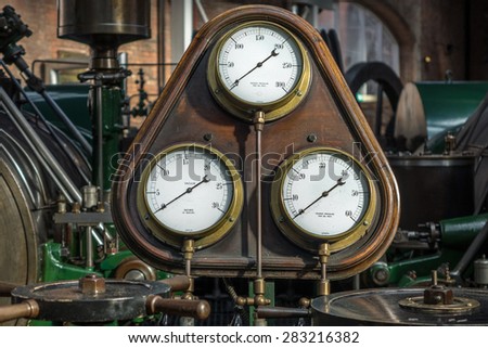 Old steam pressure gauge amid antique steam engines.