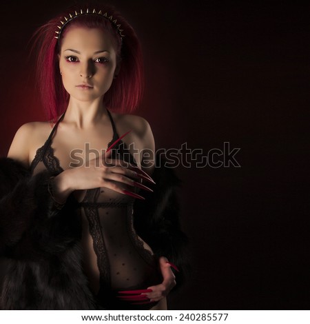 Beautiful sexy woman with red hair and long nails in fur coat and golden spike crown