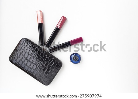 Black clutches leather bag on white background with lips gloss and a bottle of perfume