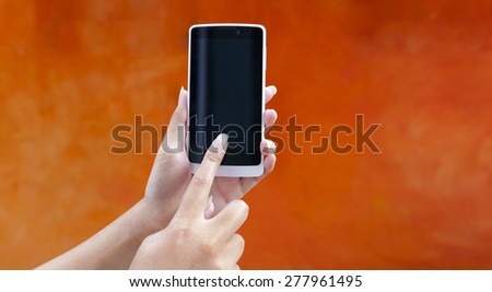 Hand holding smart phone with space on orange wall