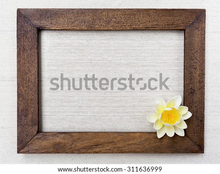 Wooden picture frame on canvas background with white flower