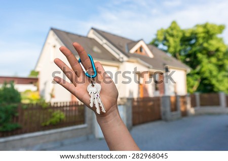 Real estate agent giving house key to a new property owner on blurred background