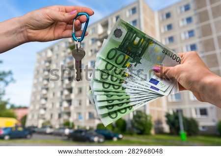 Real estate agent giving apartment keys to a new property owner, who is paying by euro money on blurred background