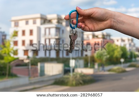 Real estate agent giving house keys to a new property owner on blurred background