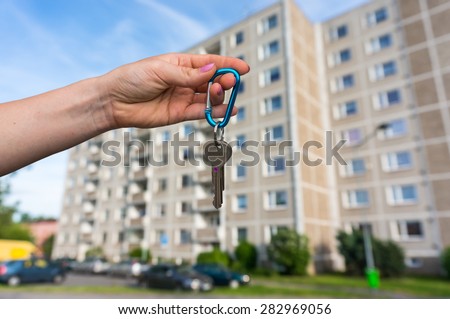 Real estate agent giving flat keys to a new property owner on blurred background