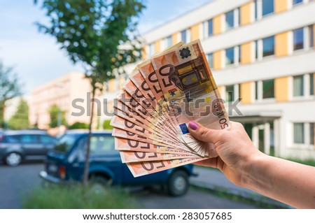Property buyer holding euro banknotes and buying beautiful flat from real estate agencies on blurred background