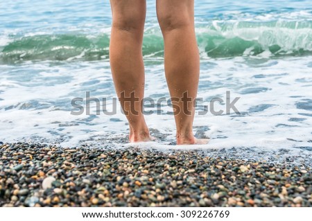Young girl standing in the water on the sea shore, she relaxes