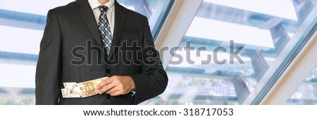 Man in business suit with money in pockets in office