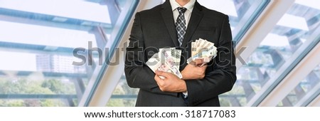 Businessman in suit with Czech and European money in office