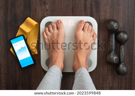 Top View Of a Person Standing On a Smart Weighing Scale, a smartphone connected to the Scale and Fitness equipment. Smart technology and health care concept