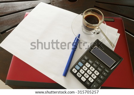 paper is on desk , blue pen with a cup of coffee and a calculator aside. Business concept