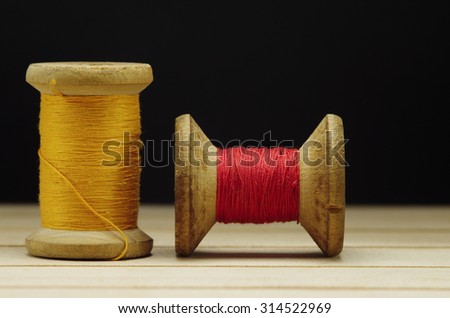 Old spool of thread with needle closeup. Tailor's work table. textile or fine cloth making.