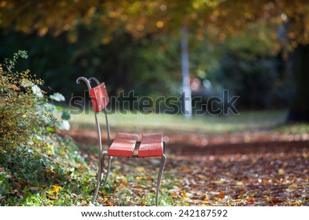 A red chair in a small park in the center of Zurich. It\'s a good place to enjoy the sunny Sunday afternoon in this late autumn.