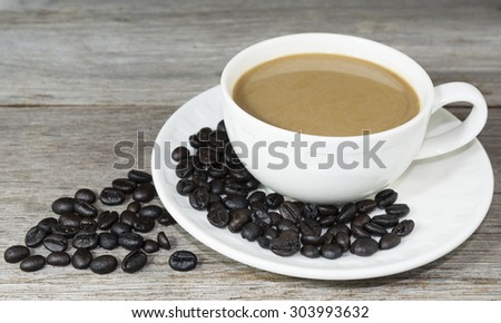 Cup of coffee and coffee beans on old wooden table, still lift
