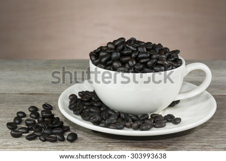 Cup filled with coffee beans on old wooden table, Vintage styled, still lift