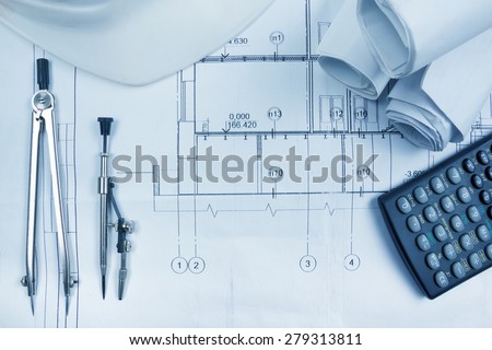 Architectural project, blueprints, blueprint rolls, compass divider, calculator, white safety on plans. Engineering tools view from the top. Copy space. Construction background. Blue toned