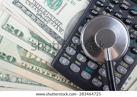 Financial analysis, audit or accounting - Stethoscope over a calculator and dollar bills. Medical costs, financial concept