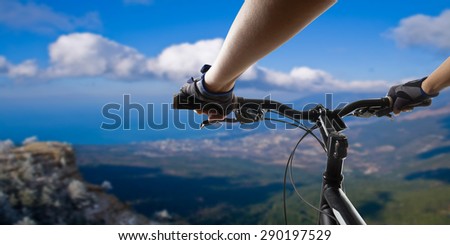 Hands in gloves holding handlebar of a bicycle. Mountain Bike cyclist riding single track. Healthy lifestyle active athlete doing sport
