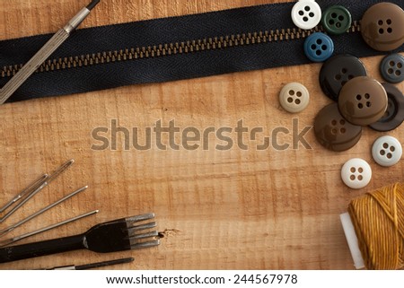 buttons, zipper  and tool on wood background