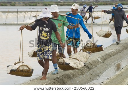 HUAHIN, THAILAND - MAY 13, 2008: Unidentified people carry baskets with salt at the salt farm on May 13, 2008 in Huahin, Thailand. Salt production is one of the main industries in Huahin area.