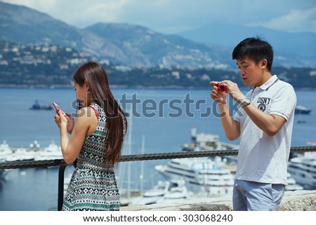 MONACO, MONACO - JUNE 06, 2015:Unidentified asian tourists check travel photos at the viewpoint in Monaco.