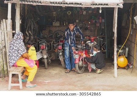 PUTHIA, BANGLADESH - FEBRUARY 16, 2014: Unidentified people fix motorbike in a workshop in Puthia, Bangladesh.