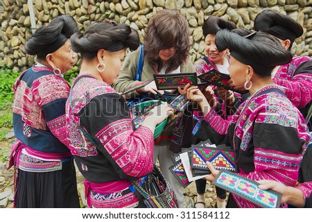 LONGJI, CHINA - MAY 06, 2009: Unidentified women sell souvenirs to a tourist in Longji, China. Women of Red Yao people living in Longji Yao village have one of the longest hair in the world.