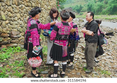 LONGJI, CHINA - MAY 06, 2009: Unidentified women sell souvenirs to a tourist in Longji, China. Women of Red Yao people living in Longji Yao village have one of the longest hair in the world.