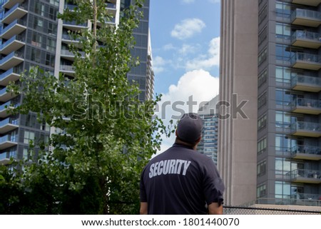Security guard looking at tall buildings