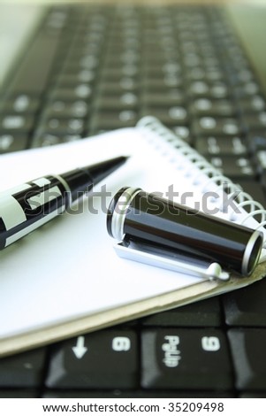 Pen on notebook and laptop computer.