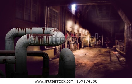 Dark alley with rusty pipes in foreground